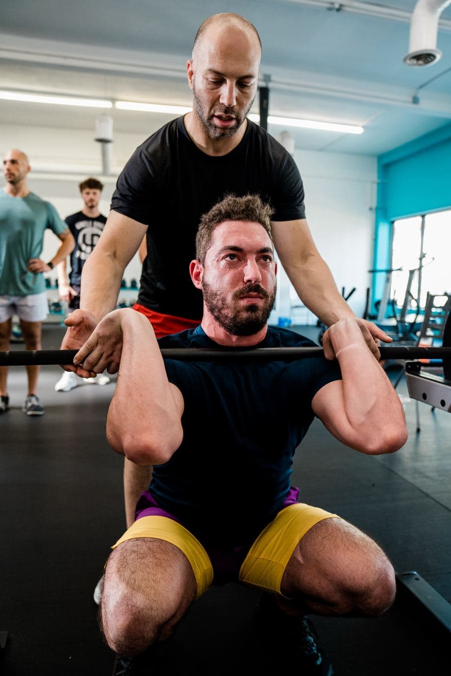 A coach guiding a client through a front squat